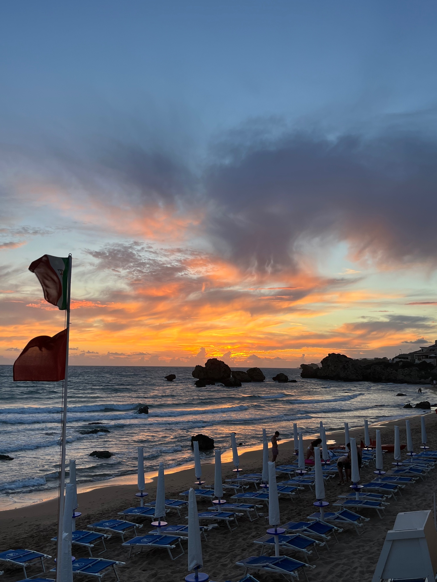 Tramonto infuocato con bandiera italiana sulla spiaggia