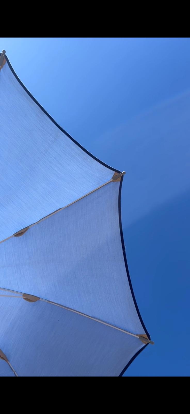 Ombrellone bianco visto dal basso contro il cielo blu